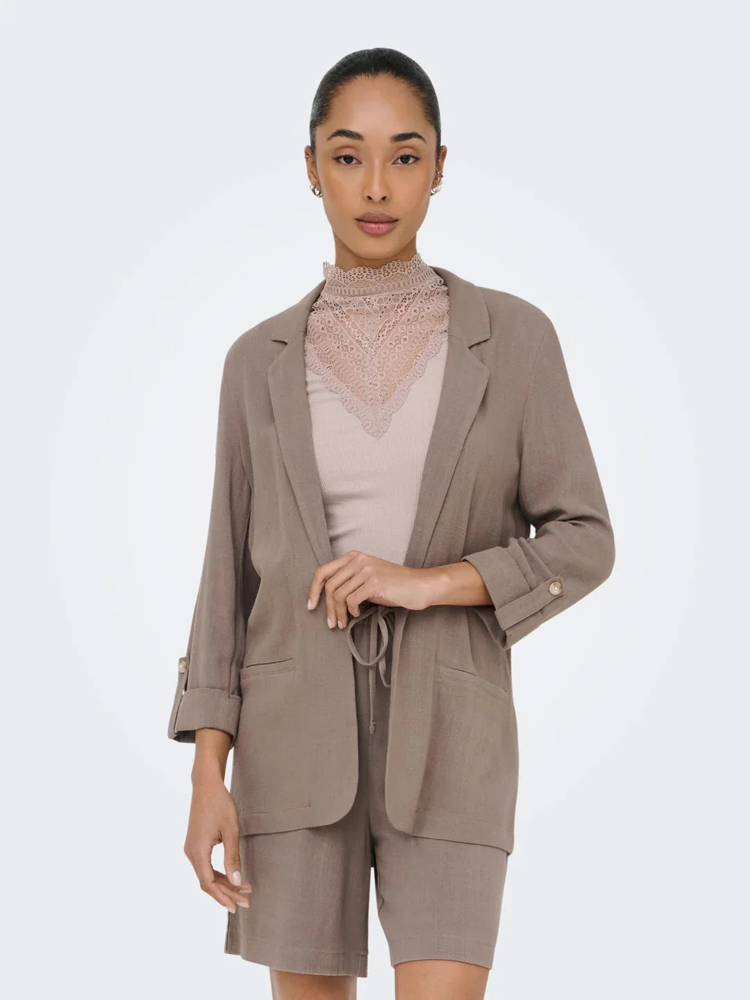 Frau mit Blazer in dunklen beige dazu passende kurze Hose und haar hochgesteckt zu engen Zopf