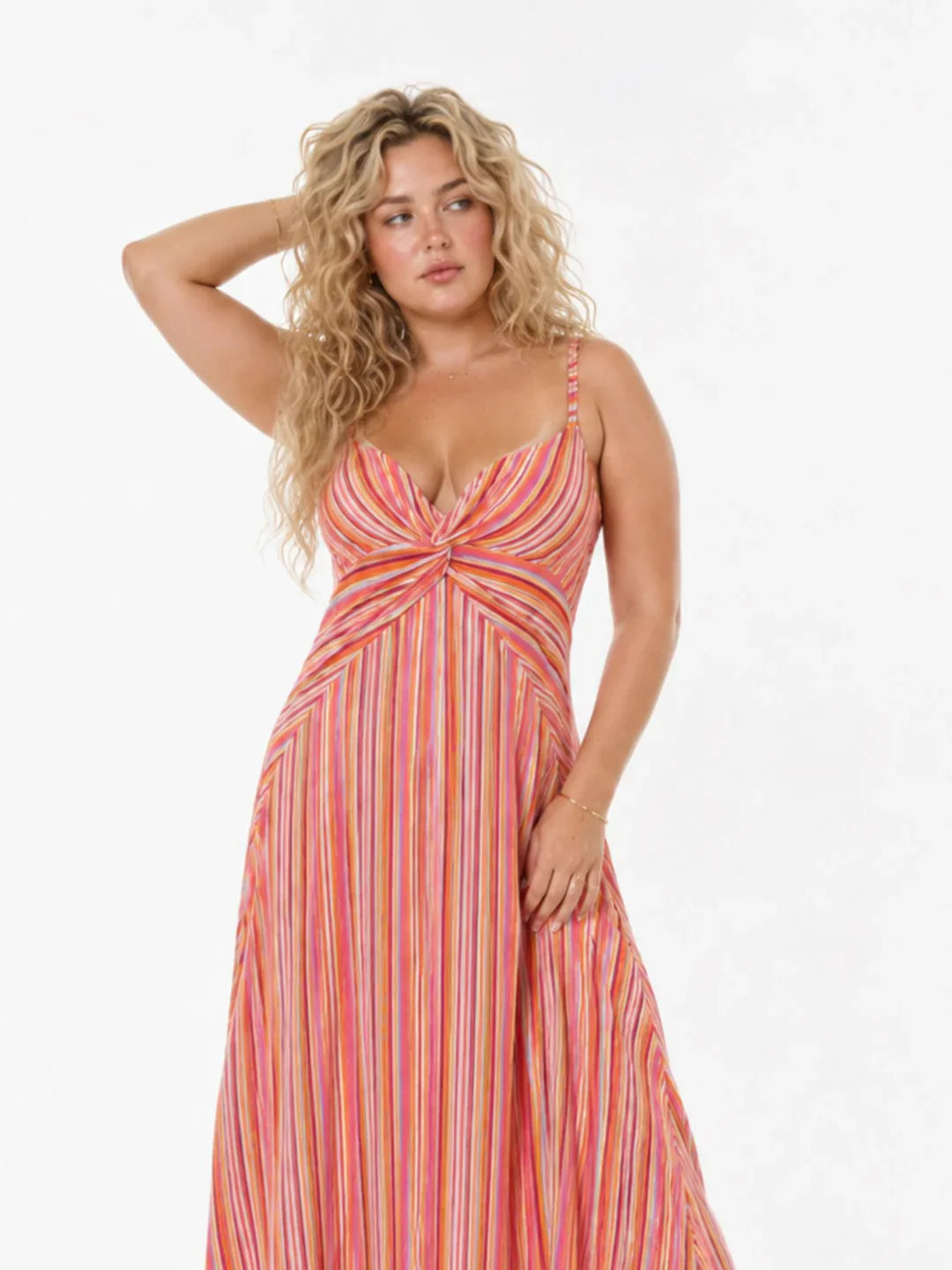 Blonde Frau in gestreiftem Sommerkleid mit Spaghettiträgern vor hellem Hintergrund.