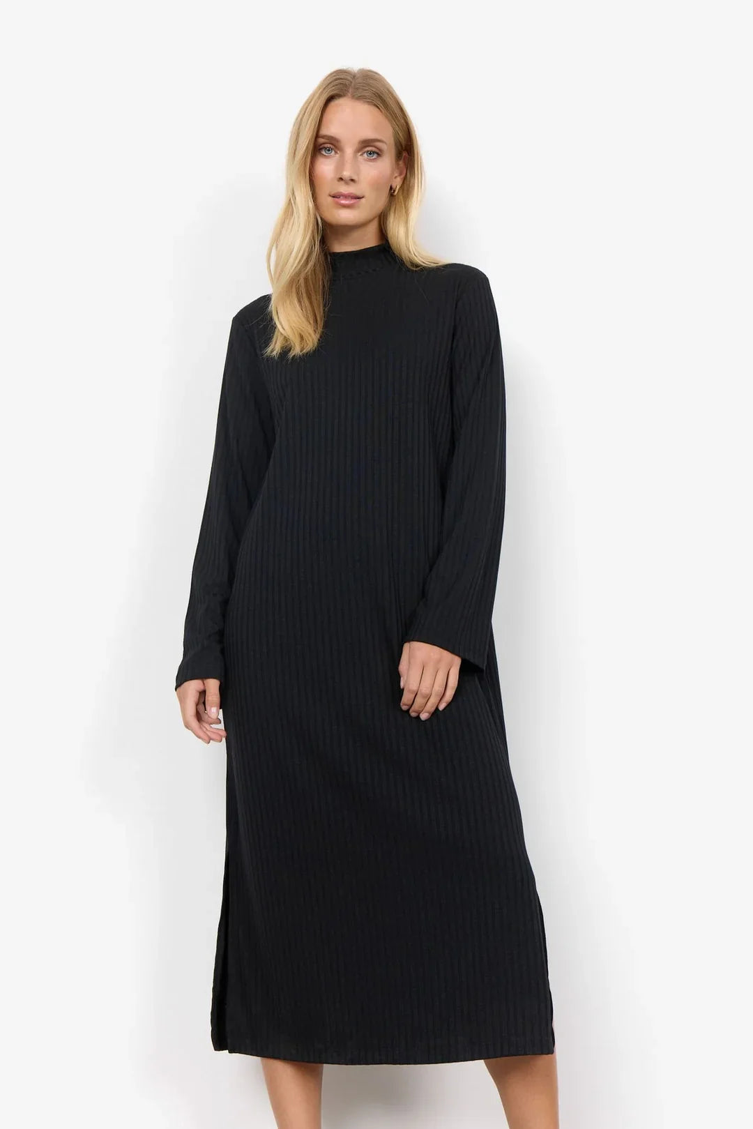 Model trägt ein schwarzes, langärmeliges Midikleid mit feiner Rippstruktur und hochgeschlossenem Ausschnitt. Der schlichte Schnitt verleiht dem Kleid einen zeitlosen, eleganten Look.