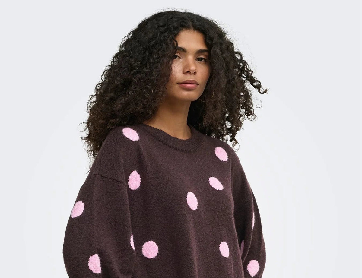 Damen-Strickpullover in Dunkelbraun mit großen rosa Punkten, locker geschnitten und modern kombiniert mit hellem Rock.