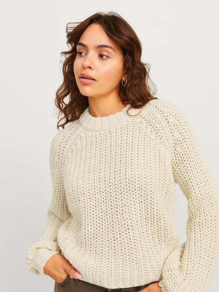 Cremeweißer Strickpullover mit Raglanärmeln – Nahaufnahme einer Frau.